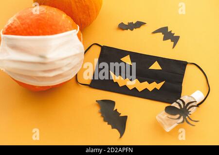 Feiern Halloween 2020 in sicherer Weise während Coronavirus Pandemie. Halloween böse Gesichtsmaske, Kürbis in Maske, Desinfektionsgel Flasche, Fledermaus und Spinne Stockfoto