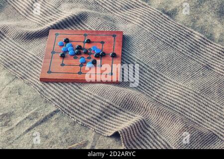Brett für das Spiel der Mühle mit den platzierten Chips. Brettspiel mit einer platzierten Position auf dem Teppich, Nahaufnahme. Stockfoto