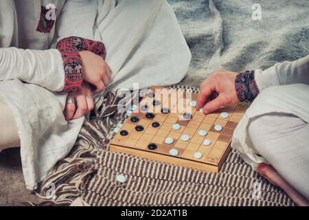 Hnefatafl - Scandinavian Brettspiel. Ein Mann und eine Frau in nationalen Kostümen spielen ähnlich wie Dame - Tavlei. Stockfoto