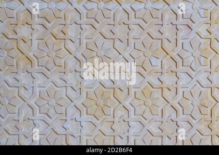 Gelber floraler Hintergrund. Textur mit Blumenmustern auf der Felsoberfläche. Textur arabisches Muster an der Steinwand. Stockfoto