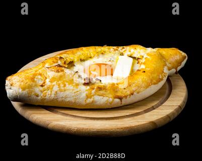 Adjarian khachapuri mit Ei und Käse. Georgische Küche. Isoliert auf schwarzem Hintergrund. Stockfoto