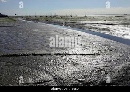 Sonnenschein glitzert auf Lehmflächen bei Ebbe Flussmündung der Themse vor Leigh on Sea Drainage Kanälen Southend Pier Boote weit entfernt von Essex England Großbritannien Stockfoto