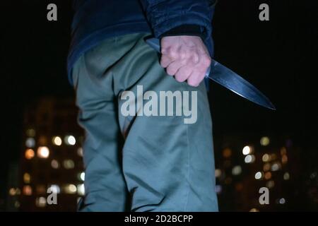 Mann mit einem Messer in den Händen in der Nacht auf der Straße Nahaufnahme. Konzept von Verbrechen, Raub Stockfoto