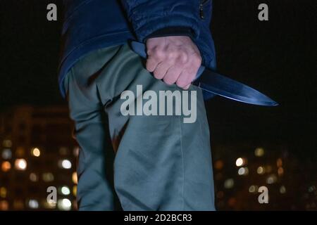 Mann mit einem Messer in den Händen in der Nacht auf der Straße Nahaufnahme. Konzept von Verbrechen, Raub Stockfoto