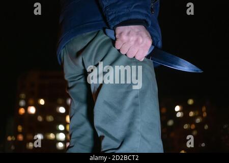 Mann mit einem Messer in den Händen in der Nacht auf der Straße Nahaufnahme. Konzept von Verbrechen, Raub Stockfoto