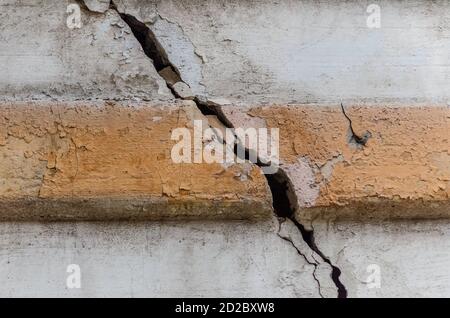 Ein Riss in der Betonwand des Hauses mit Ein gelber Streifen in der mittleren Nahaufnahme Stockfoto