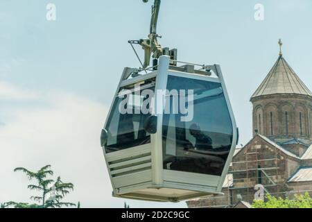 Tiflis, Georgien, Standseilbahn-Taxi Nahaufnahme gegen den blauen Himmel, die Krone eines Baumes und die Kirche Stockfoto