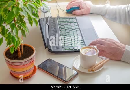 Ein Mann arbeitet zu Hause an einem Computer. Remote-Arbeit, soziales Distanzierungskonzept. Stockfoto