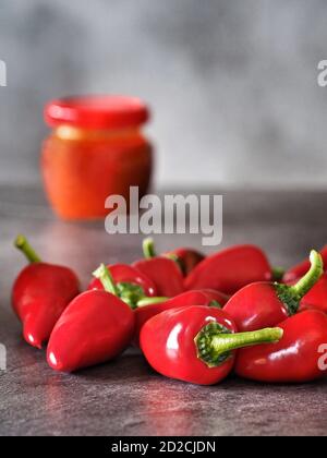 Rote scharfe Chilischoten und Ajvar (Pfeffermousse) auf dunklem Hintergrund. Stockfoto