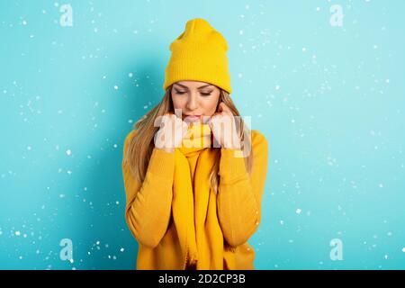 Frau hält warm mit Schal und Hut im Winter. Cyanfarbener Hintergrund Stockfoto