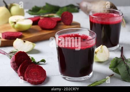 Zwei Gläser frischer Saft mit Rote Bete und Äpfeln. Gehackte Rüben und Äpfel auf grauem Tisch. Nahaufnahme. Horizontales Format Stockfoto