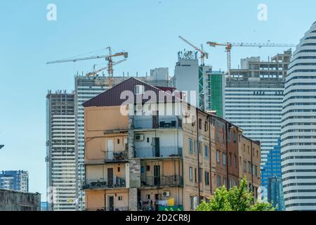 Tiflis, Georgien - 1. Juli 2019: Alte Häuser vor dem Hintergrund des Baus moderner Glasgebäude in Batumi, Georgien. Stockfoto