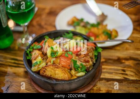 Traditionelle georgische Familie Essen ojakhuri, gebratenes Fleisch mit Kartoffeln und Gemüse in einer Keramik-Topf Nahaufnahme, leckere Küche Stockfoto