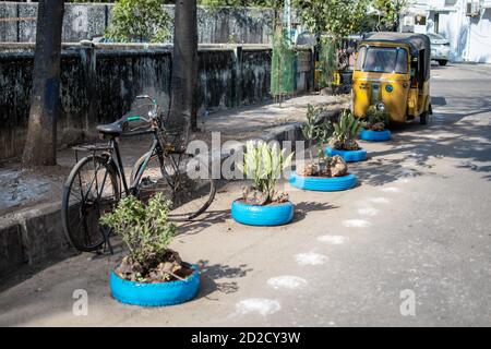 Chennai, Indien - 8. Februar 2020: Ein Fahrrad und eine traditionelle gelbe Auto-Rikscha geparkt auf der Straße durch blaue dekorative Reifen am 8. Februar 2020 Stockfoto