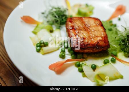 Gegrilltes Lachsfilet mit Salat auf einem weißen Teller Stockfoto