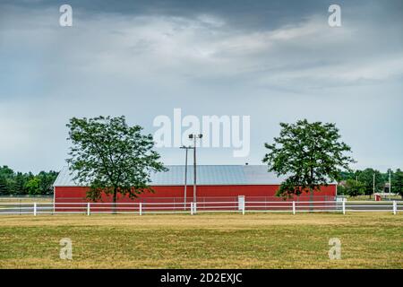 Roter Metallschuppen und weißer Eisenbahnzaun Stockfoto