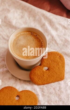 Vertikale Aufnahme einer Tasse Kaffee und herzförmige Kekse Stockfoto