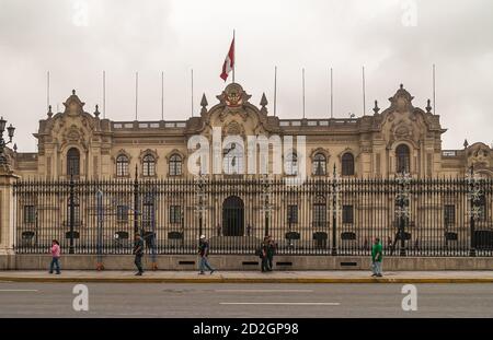 Lima, Peru - 4. Dezember 2008: Regierungspalast von der Plaza Major aus gesehen. Hellbraunes Gebäude unter silbernem Himmel. Schwarzer Metallzaun vorne mit Sockel Stockfoto