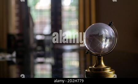 Transparenter Globus auf einem schwarzen Glastisch Stockfoto