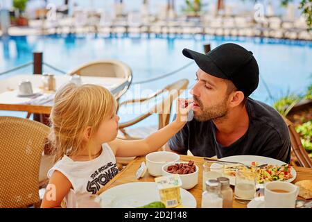 Kleine Tochter füttert ihren Vater Stockfoto