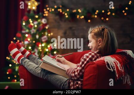 Frohe Weihnachten! Nettes kleines Mädchen schreibt den Brief an den Weihnachtsmann. Stockfoto