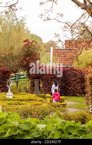 Ein malerischer Park in Den Haag mit dekorativ bedruckten Sträuchern auf jeder Seite der Wanderwege. Eine Mutter und ihr Kind gehen an diesem friedlichen Ort mit Stockfoto