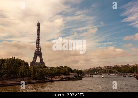 Malerische Aussicht auf Paris, Frankreich im Frühling mit der seine auf der einen Seite und dem berühmten Eiffelturm auf der anderen. Eine kleine Fußgängerbrücke aus Metall, Bäume, Stockfoto