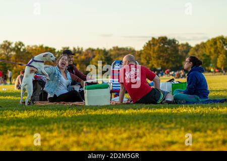 Arlington, VA, USA 10/02/2020: Eine multirassische Gruppe junger Menschen sitzen auf zusammenklappbaren Stühlen oder Laken auf dem Grasfeld des Gravelly Point Parks. Th Stockfoto