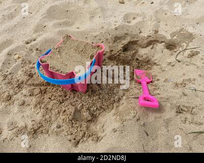 Pink Basket und Spaten auf Great Yarmouth Strand in einem kalten Sommertag, traditionelle englische Küste, Himmel mit Wolken keine Menschen, große Strecke des Sandes, Großbritannien sein Stockfoto