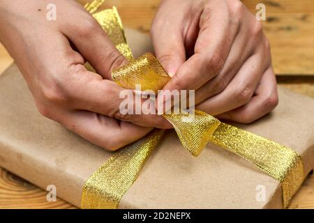 Eine weibliche Hände wickeln ein Weihnachtsgeschenk. Machen Sie Weihnachtsgeschenke. DIY Weihnachtsgeschenke an Freunde und Familie Stockfoto