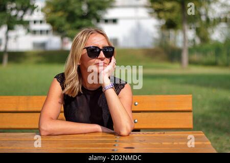 Porträt der reifen blonden Frau auf einer Bank sitzen Stockfoto