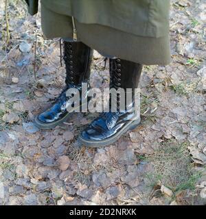 Weibliche Beine tragen Herbststiefel stehen auf dem Boden bedeckt Mit Herbstblättern Stockfoto