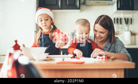 Glückliche kaukasische Familie bereitet Cookies für weihnachten zu Hause waring weihnachtsmann Kleidung und Hut Stockfoto