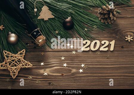 Neujahr 2021. Tannenzweige mit goldenen Zahlen, Champagner und Dekorationen auf Holzgrund. Festliche Weihnachten Hintergrund. Speicherplatz kopieren. Flach liegend. Stockfoto