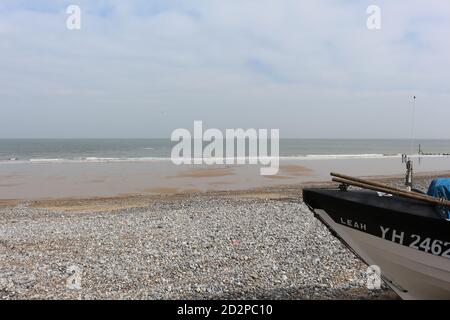 Fischerboote auf dem Sandstrand von Cromer an einem sonnigen Wintertag, Muschel Meer mit sanften Wellen krachend auf den Strand Stockfoto