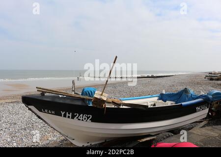 Fischerboote auf dem Sandstrand von Cromer an einem sonnigen Wintertag, Muschel Meer mit sanften Wellen krachend auf den Strand Stockfoto