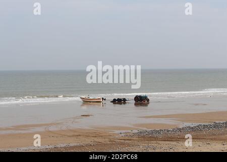 Fischerboote auf dem Sandstrand von Cromer an einem sonnigen Wintertag, Muschel Meer mit sanften Wellen krachend auf den Strand Stockfoto