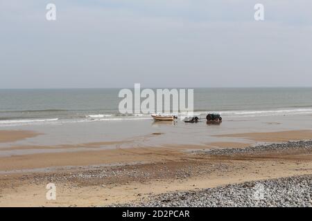 Fischerboote auf dem Sandstrand von Cromer an einem sonnigen Wintertag, Muschel Meer mit sanften Wellen krachend auf den Strand Stockfoto