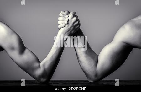 Zwei Männerhände umklammten Arm Wrestling, stark und schwach, ungleiche Übereinstimmung. Armdrücken. Schwer muskulös Mann Arm Wrestling ein mickrigen schwachen Mann. Schwarz und Stockfoto