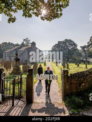 Die Trauerdirektoren Tim Twigger und Sarah Jones von Full Circle Beerdigungen, mit einer Blumenbehrung, die "Admin" lautet, in der Weston Church in Otley, West Yorkshire, während Aktivisten die Regierung aufrufen, einen neuen Trauerstandard einzuführen, um die Verwaltung am Ende des Lebens zu vereinfachen, die nach dem Verlust eines Verwandten erforderlich ist. Stockfoto