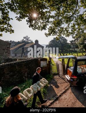 Die Trauerdirektoren Tim Twigger und Sarah Jones von Full Circle Beerdigungen, mit einer Blumenbehrung, die "Admin" lautet, in der Weston Church in Otley, West Yorkshire, während Aktivisten die Regierung aufrufen, einen neuen Trauerstandard einzuführen, um die Verwaltung am Ende des Lebens zu vereinfachen, die nach dem Verlust eines Verwandten erforderlich ist. Stockfoto