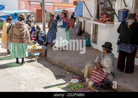 Straßenhändler tragen traditionelle Kleidung und Melone Hüte verkaufen frisches Obst und Gemüse an der Copacabana in Bolivien. Stockfoto