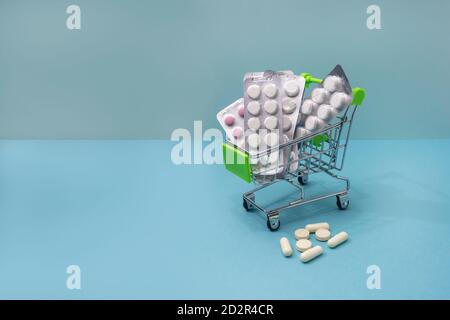 Medizinisches Shopping-Konzept. Verschiedene Pillen und Medikamente in einem Warenkorb. Platz auf blauem Hintergrund kopieren. Stockfoto