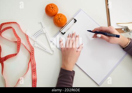 Ernährungsberater Arzt schriftlich Diät-Plan auf dem Tisch mit Maßband, Blick von oben Stockfoto