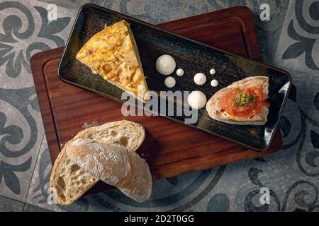 Spanisches Omelett serviert mit etwas Sahne und Brot mit Tomatentapenade Stockfoto