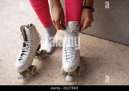 Schlanke weibliche sitzen auf der Bank und binden Schnürsenkel auf Roller Schlittschuhe Stockfoto