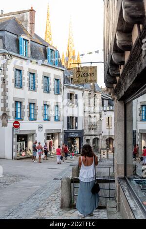 Quimper, Frankreich - 2. August 2018: Frau auf der Straße inmitten alter Gebäude und Geschäfte im Zentrum von Quimper, der Hauptstadt der Finistere Abfahrt Stockfoto