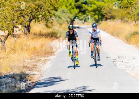 Die ganze Länge der Radfahrer in Sportbekleidung und Helme zusammen Radfahren Auf asphaltierter Fahrbahn im Sommer auf dem Land Stockfoto