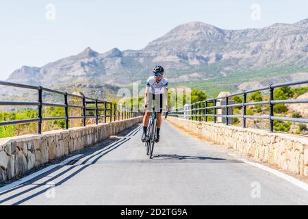 Volle Länge der aktiven weiblichen Radfahrer in Helm und Sportbekleidung Radfahren auf Asphaltstraße in der Nähe Bergrücken im Sommer Tag Stockfoto