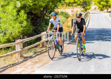 Die ganze Länge der Radfahrer in Sportbekleidung und Helme zusammen Radfahren Auf asphaltierter Fahrbahn im Sommer auf dem Land Stockfoto